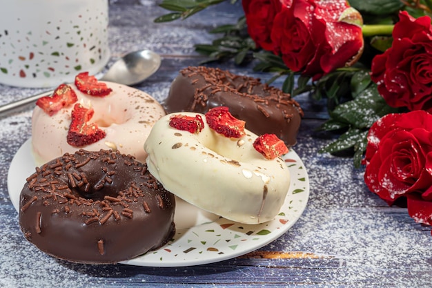 Handgemaakte donuts op een lichte achtergrond in witte en zwarte chocolade. Er zijn bloemen in de buurt. Vrouwendag, Valentijnsdag.