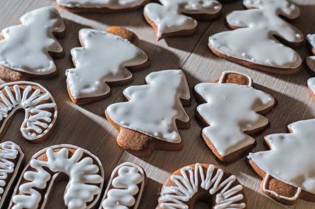 Handgemaakte feestelijke peperkoekkoekjes in de vorm van sterren, personeel, kerstbomen. Op een licht aanrecht.