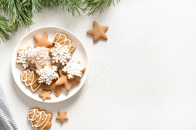 Handgemaakte geglazuurde kerstkoekjes in plaat ingericht fir takken op witte achtergrond. Uitzicht van boven. Plat leggen.