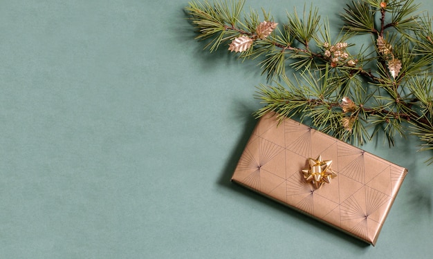 Handgemaakte geschenkdoos verpakt in glanzend eco-vriendelijk papier, kerstboomtak met glanzende kerstballen.