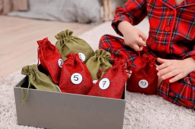 Handgemaakte groene en rode zakjes adventskalender en een kind met een zakje