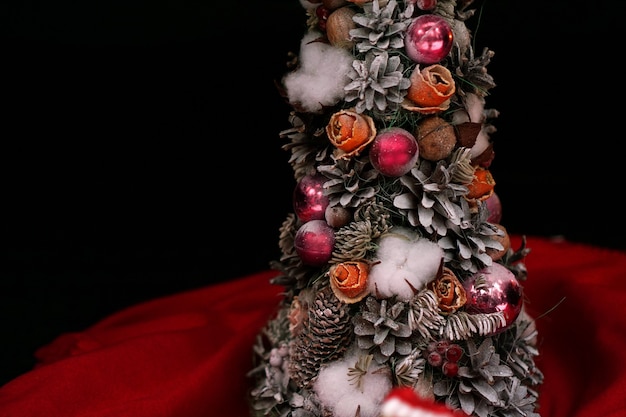Handgemaakte kerstboom met kegels en roze kerstballen op donkere achtergrond