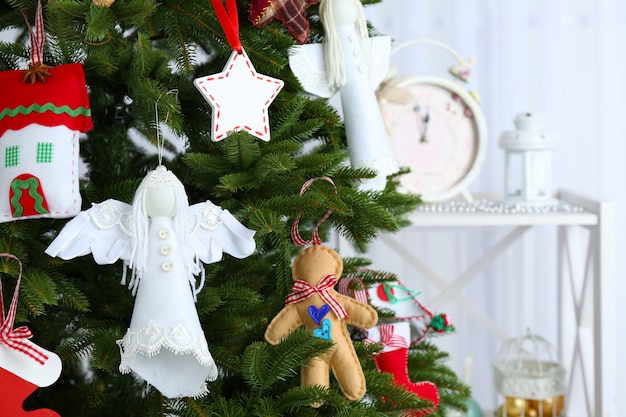 Handgemaakte kerstversieringen op kerstboom op lichte ondergrond