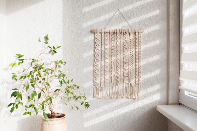 Handgemaakte macrame 100 katoenen wanddecoratie met houten stok hangend aan een witte muur macrame vlechten en katoenen draden vrouwelijke hobby eco-vriendelijk modern breien natuurlijke decoratie in interieur