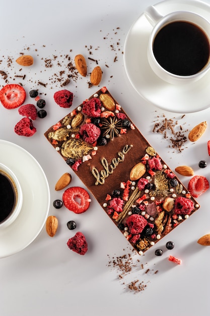 Handgemaakte melkchocolade met gevriesdroogde bessen en noten, natuurlijk op een witte achtergrond