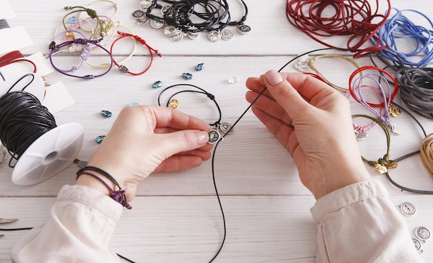 Handgemaakte sieraden maken, vrouwelijke hobby. vrouw die armband maakt thuis workshop, artisanale pov. mode, handwerkconcept