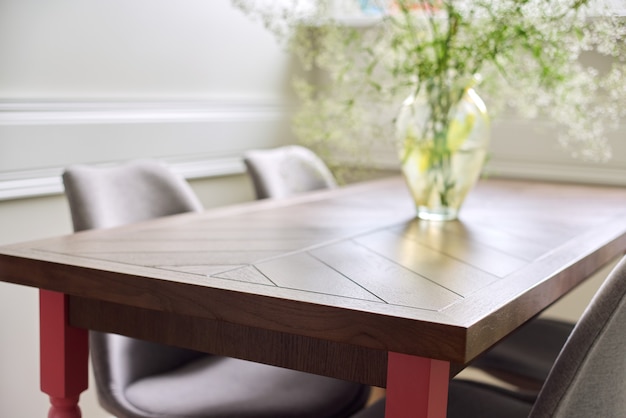 Handgemaakte timmerlieden houten eiken tafel in het interieur van de woonkamer, op tafelvaas met bloemen, stoelen