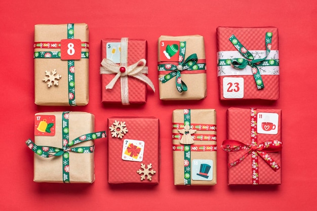 Handgemaakte verpakte rode, groene geschenkdozen versierd met linten, sneeuwvlokken en cijfers, kerstversiering en decor op tafel Xmas adventkalender concept Bovenaanzicht Plat lag Kerstkaart