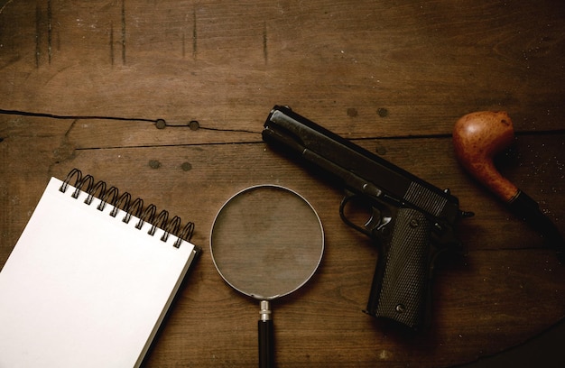 Handgun and a blank notepad on wooden background