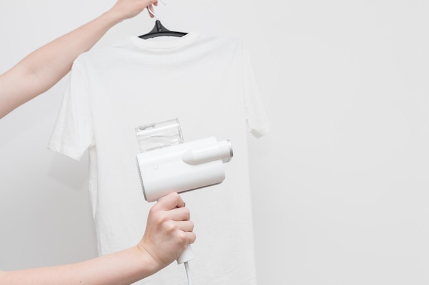 Handheld clothes steamer with white Tshirt on a light background