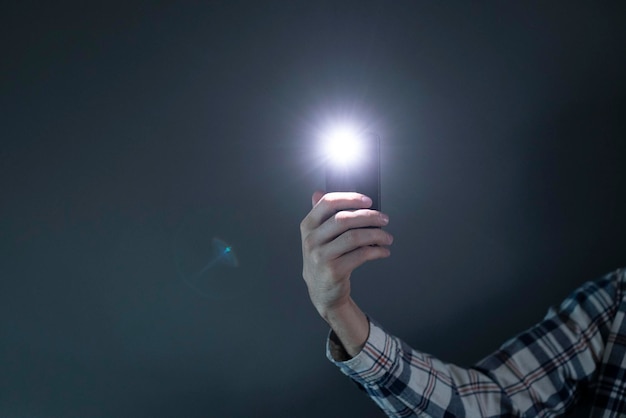 Handholding smartphone gebruikt als zaklamp met zaklamp van mobiele telefoon in het donker