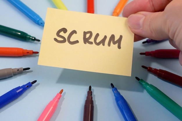 Handhoudende sticker met scrum inscriptie en veel potloden rond teamwerk