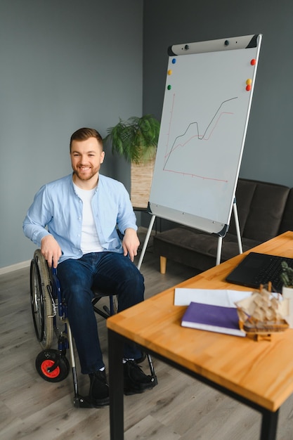 Handicapped Businessman Sitting On Wheelchair And Using Computer In Office