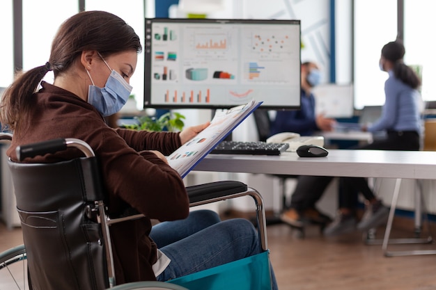 Imprenditrice portatrice di handicap che indossa una maschera facciale di protezione medica contro il coronavirus