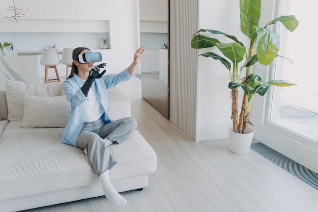 Handicapped girl with cyber arm in vr glasses at home Technology for recovery and rehabilitation