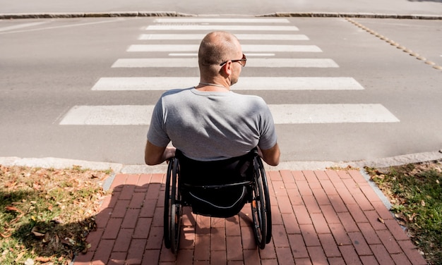 Handicapped man in wheelchair preparing to cross the road on pedestrian crossing.