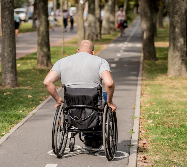 Handicapped man in wheelchair walk at the park alley.