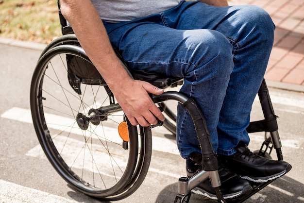 Uomo disabile in sedia a rotelle a piedi al vicolo del parco