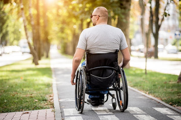 Handicapped man in wheelchair walk at the park alley