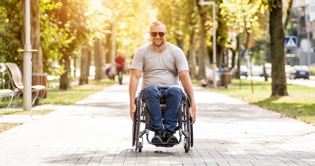 Handicapped man in wheelchair walk at the park alley