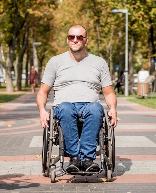 Handicapped man in wheelchair walk at the park alley