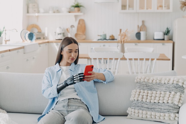 Handicapped woman is texting on smartphone Happy girl holding the phone with bionic artificial arm