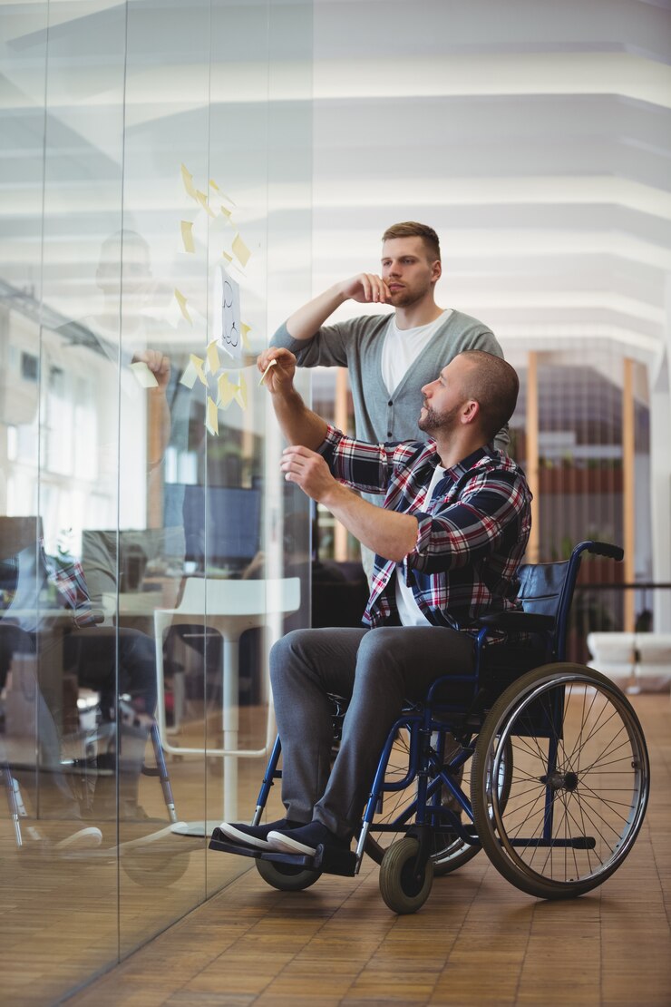 Foto handicapzakenman en collega die zelfklevende nota's plakken in bureau