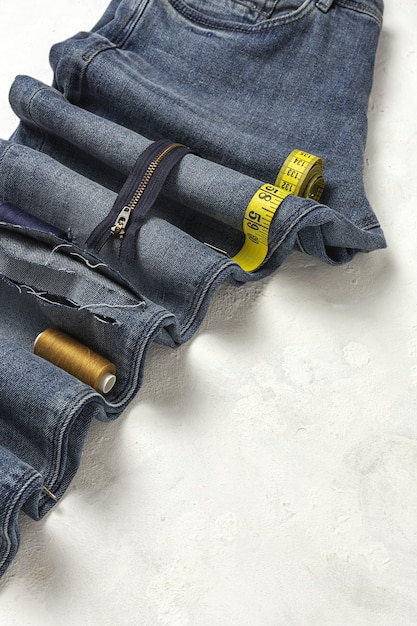 Handicraft, clothing repair. Ripped blue jeans sewing accessories from above. Flat lay
