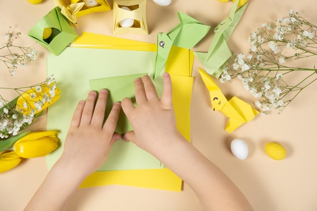 Handicrafts from paper for Easter origami making figurines of Easter bunnies child hands closeup