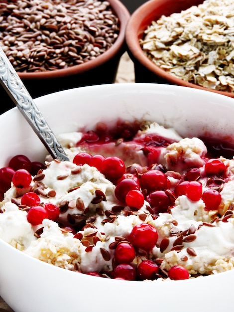 Handig ontbijt. Havervlokken met witte yoghurt, jam, lijnzaad en veenbessen. Het concept van een gezond dieet.