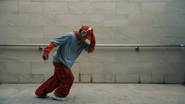 Foto handige choreograaf oefent straatdans op een grijze achtergrond.