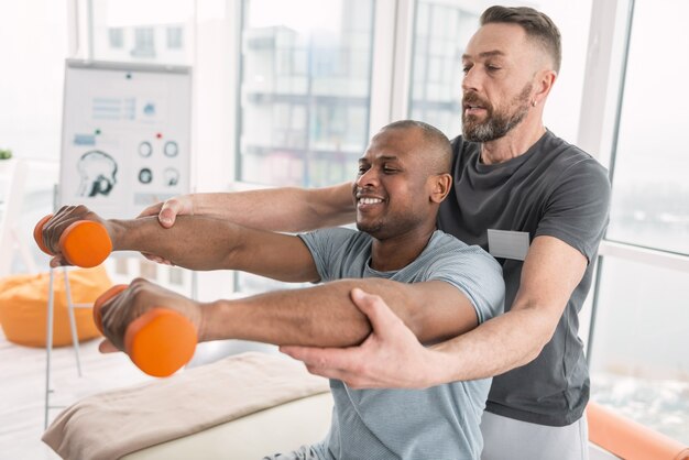 Handige therapie. Vrolijke positieve man die lacht terwijl hij geniet van de lichamelijke oefening