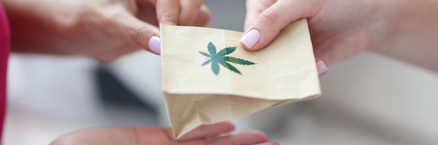 Handing over paper bag with marijuana sign