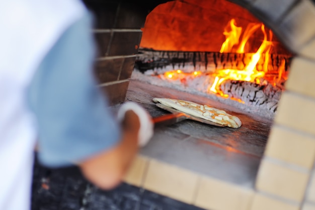 Handkok of bakker met smakelijke pizza