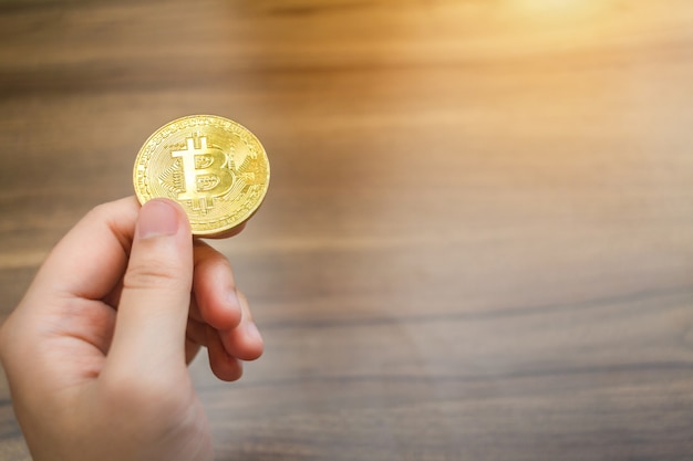 Handle of Bitcoin coin on wooden floor background.