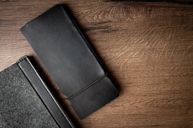 Handmade black wallet made of genuine leather on a wooden background Closeup top view