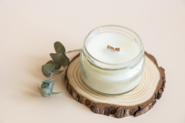 Handmade candle from paraffin and soy wax in glass with wooden wick and dry herbal isolated on pastel beige background Flat lay top view copy space