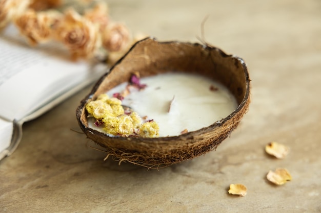 Handmade candle from soy and coconut wax in glass with wooden wick and dry flowers isolated on pastel beige background Flat lay top view copy space