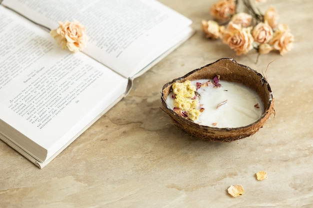 Handmade candle from soy and coconut wax in glass with wooden wick and dry flowers isolated on pastel beige background Flat lay top view copy space