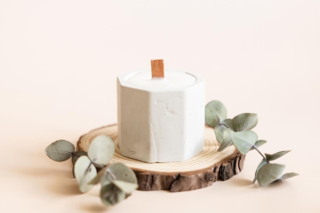 Handmade candles from paraffin and soy wax in concrete plaster candlestick with wooden wick and dry herbal isolated on pastel beige background Copy space