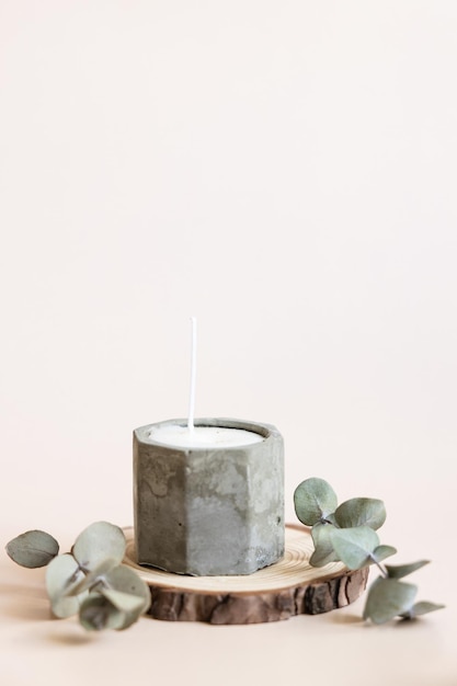 Handmade candles from paraffin and soy wax in concrete plaster candlestick with wooden wick and dry herbal isolated on pastel beige background Copy space