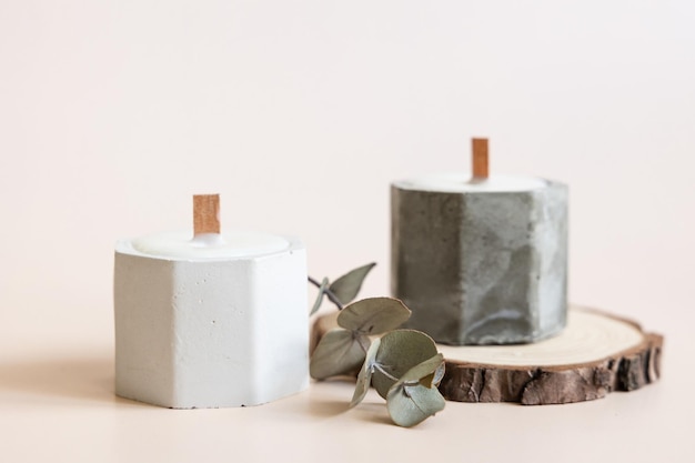 Handmade candles from paraffin and soy wax in concrete plaster candlestick with wooden wick and dry herbal isolated on pastel beige background copy space