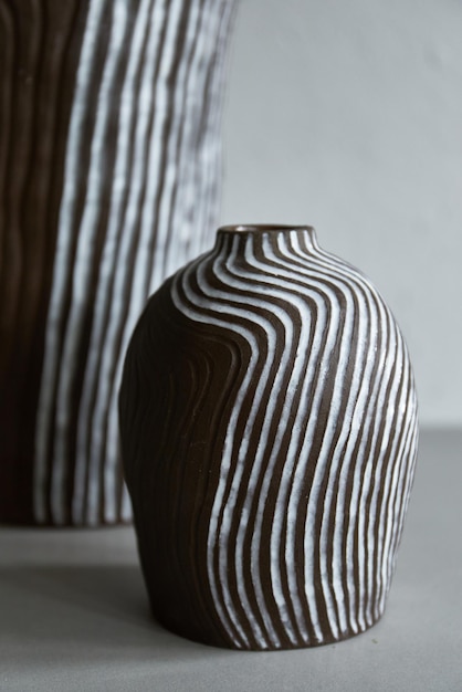 Handmade ceramic vase standing on grey table on light background. Art of clay. The process of creating pottery