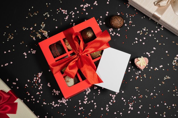 Handmade chocolate truffle candies in a red box on a dark background with business card