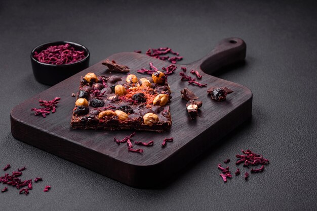 Handmade chocolate with berries nuts and spices on a dark background