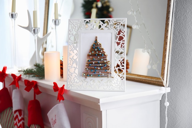 Handmade Christmas tree in photo frame on mantelpiece