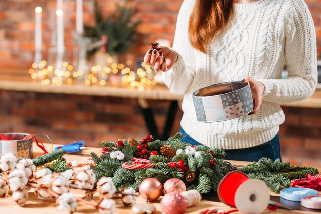 手作りのクリスマスリース。冬の装飾に松ぼっくりを使用している女性の花屋。