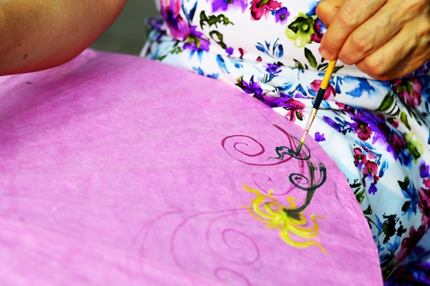 Фото Концепция ручной работы: азиатская краска для женщин на шелковом бумажном зонтике с кистью.