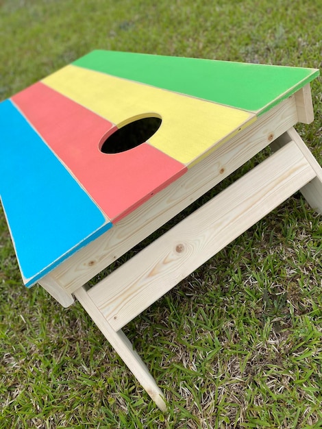 Photo handmade cornhole board game rainbow multi-colored sitting in a yard of grass