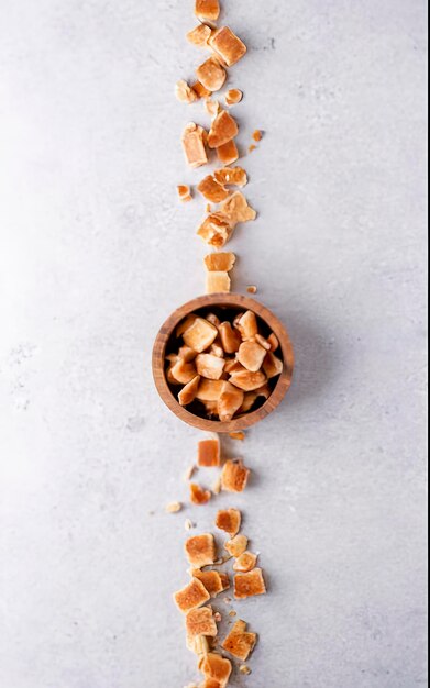 Handmade crumbly fugde in a wooden bowl over white background Top view